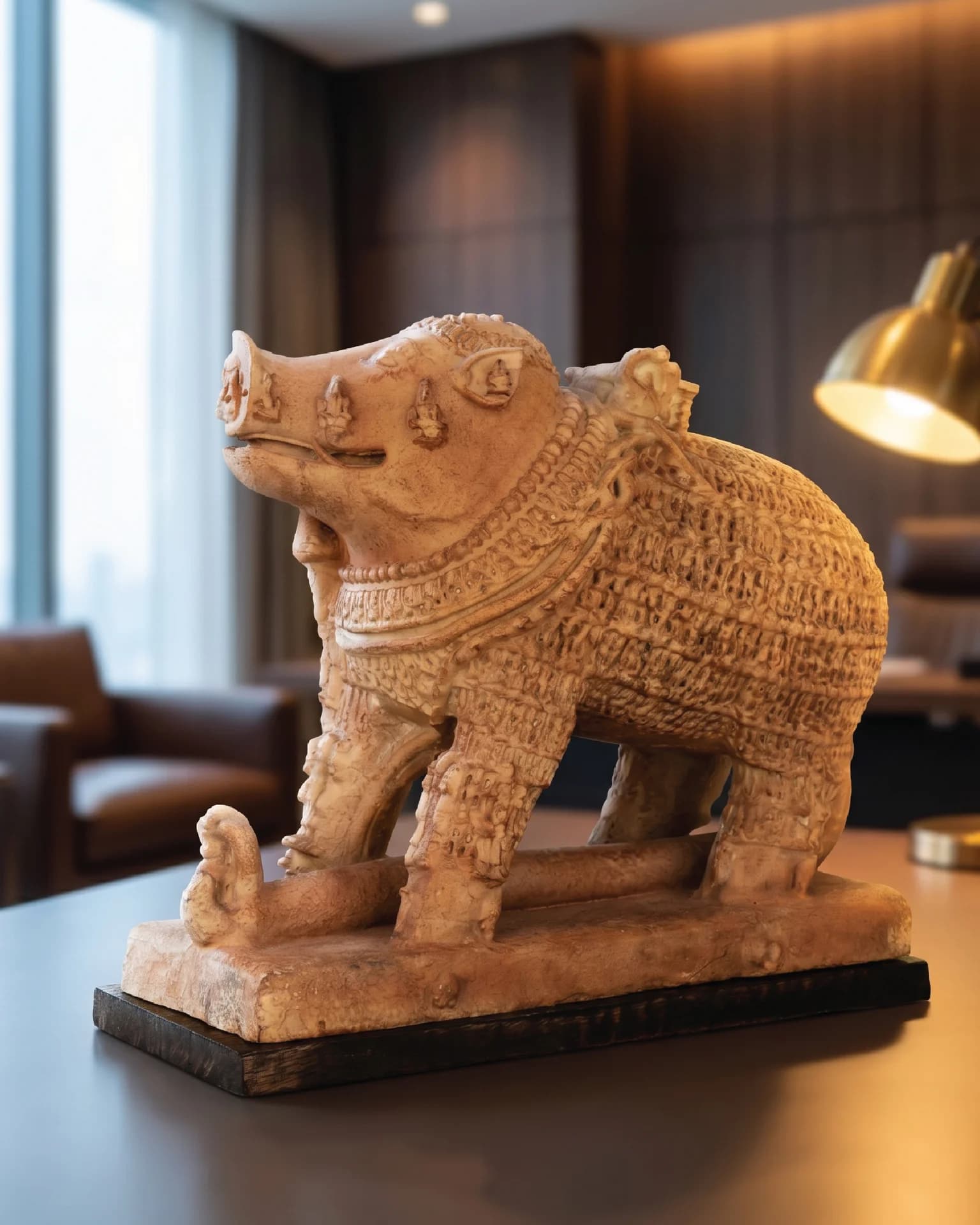 A side-profile view of the Adi Varaha Sculpture, a sandstone museum replica featuring intricate carvings of deities on the boar.