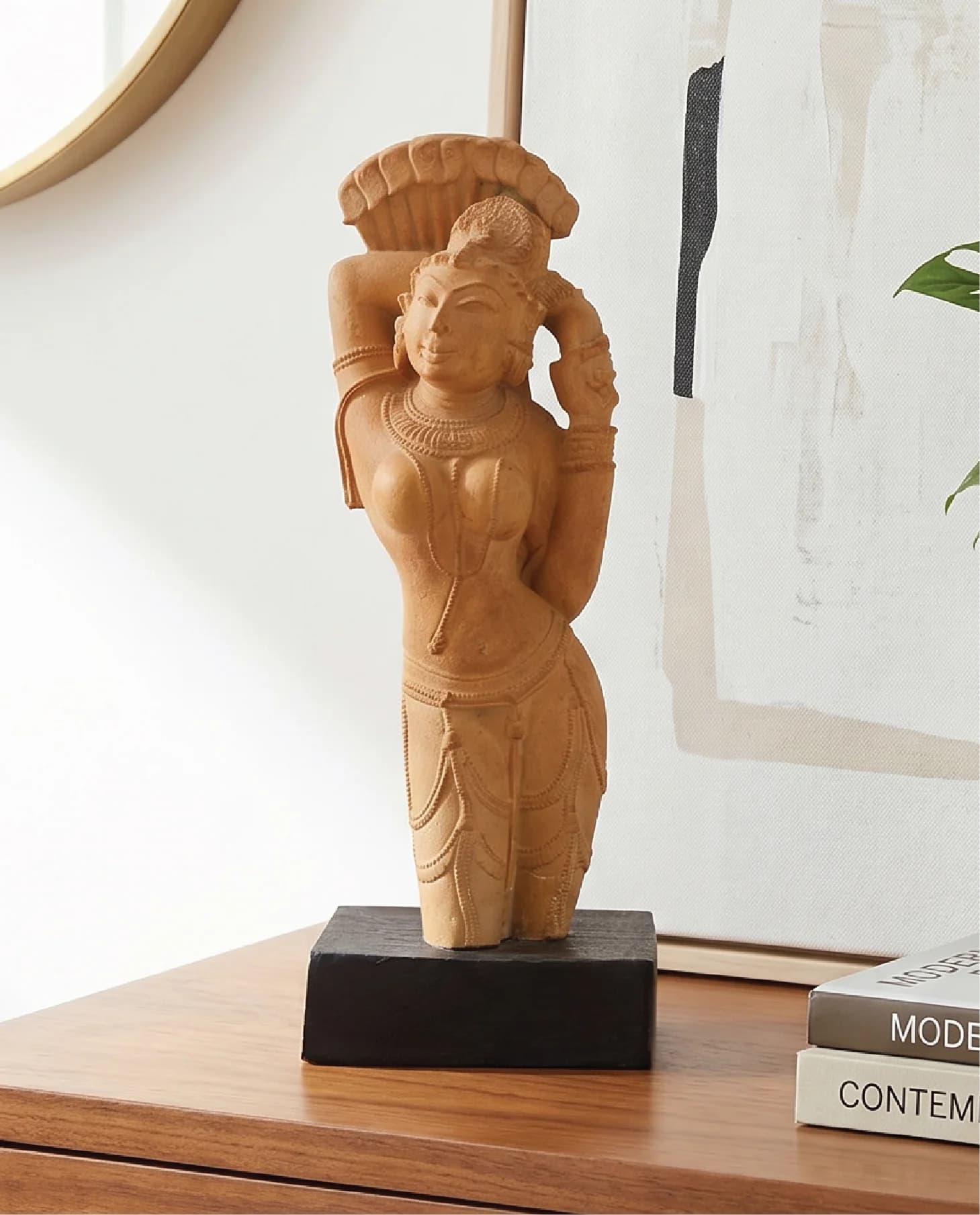 The Alasa Nayika Sculpture, a hand-finished stone composite replica, stands elegantly on a wooden table in a modern room.