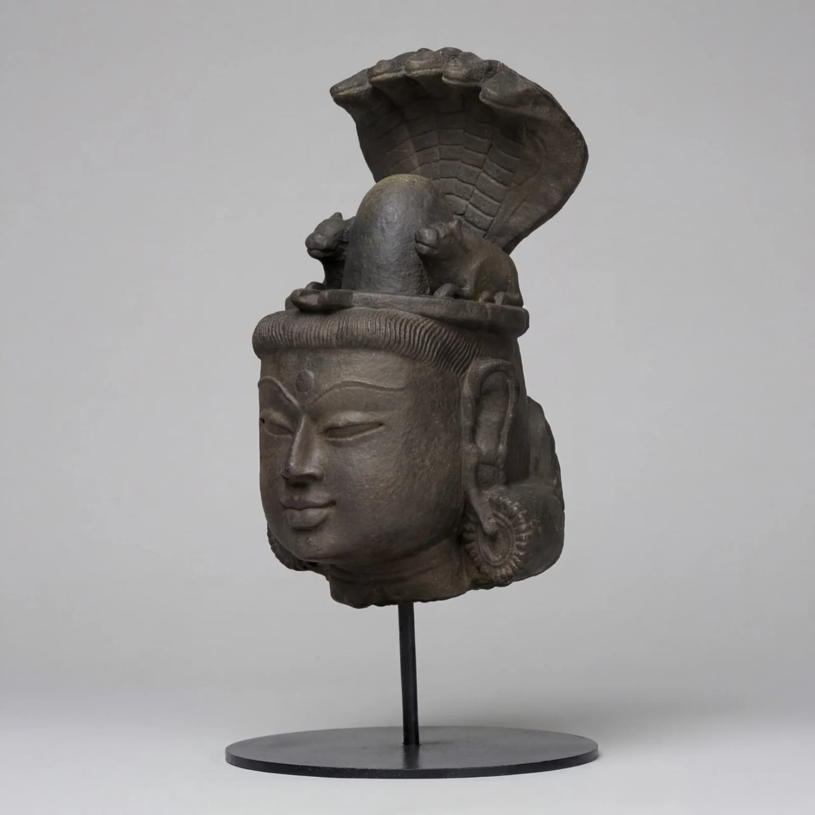 A stone composite Shiva Lingam with Nandi & Serpent replica featuring a serene deity head with intricate carvings.