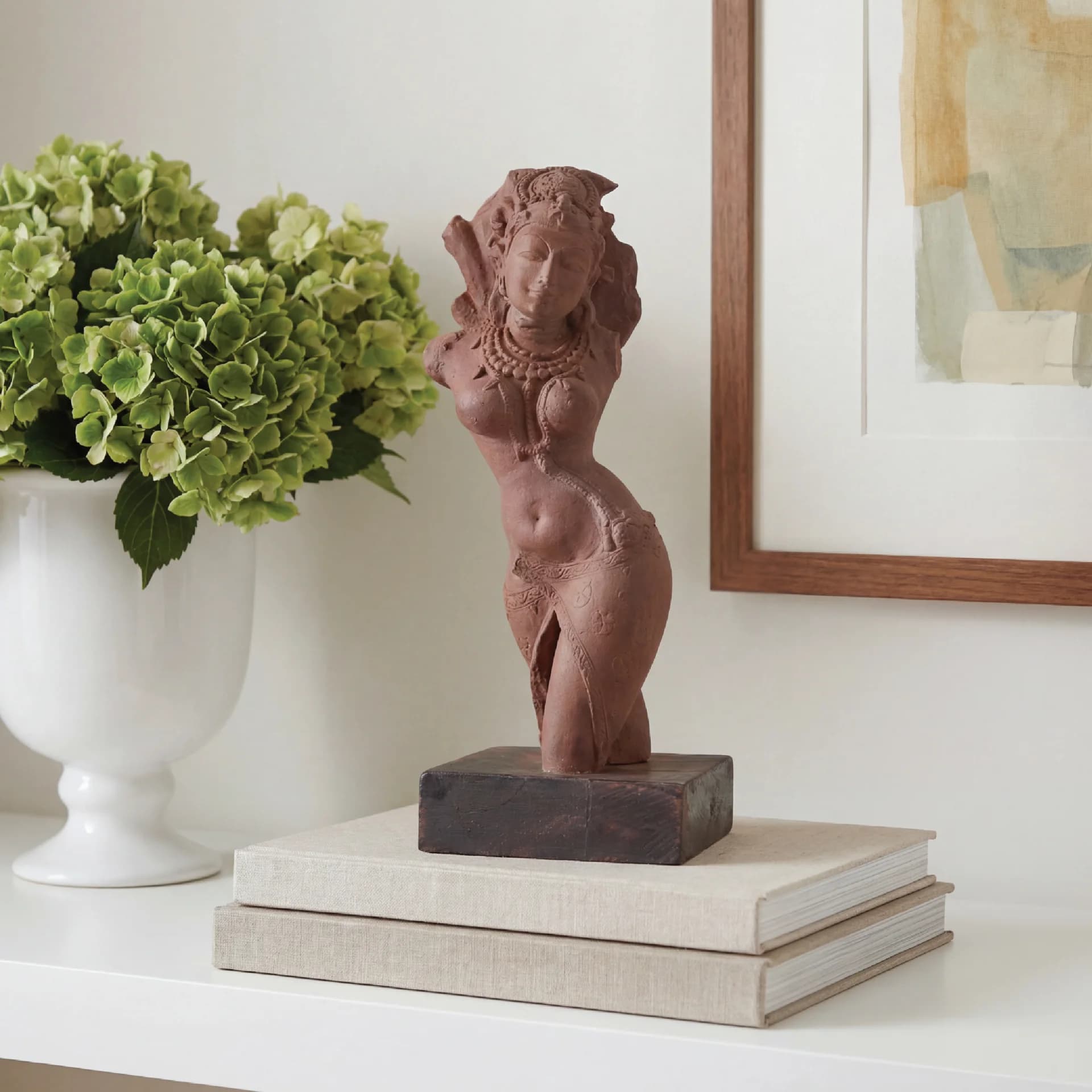 The Salabhanjika Sculpture, a stone composite museum replica, stands elegantly on a wooden base atop stacked books.